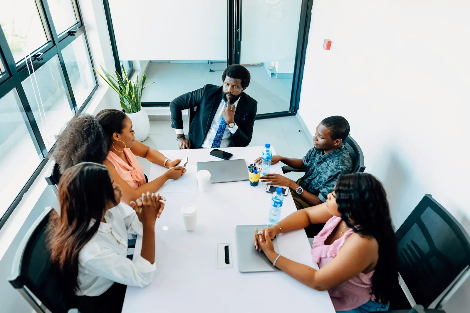 Five professionals in a meeting around a table in a bright office in Lagos