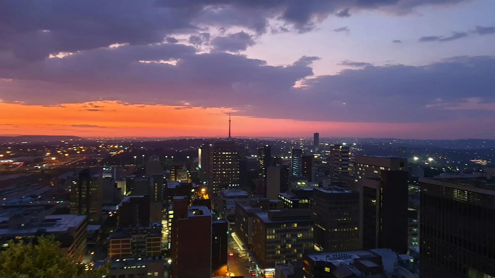 Johannesburg buildings at dusk seen from Braamfontein under an orange and purple sky