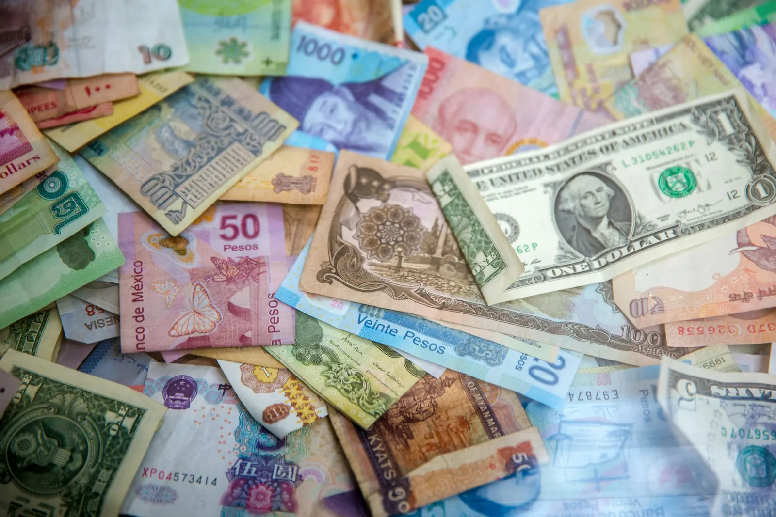Banknotes from many different currencies spread out and overlapping