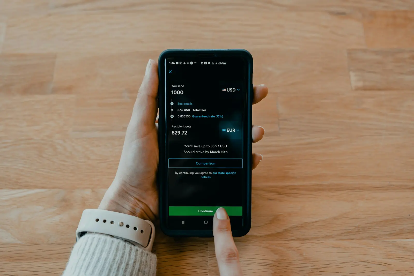 Hand holding a smartphone displaying an international money transfer app converting US dollars to euros