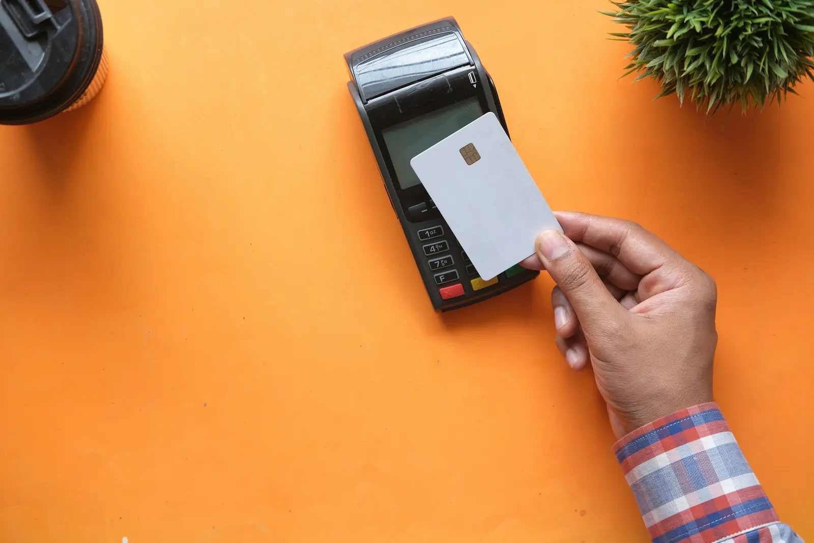 Hand holding a blank chip card over an electronic payment terminal